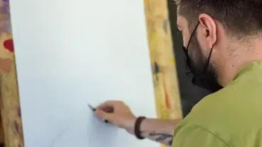 Künstler mit schwarzer medizinischer Maske bei der Arbeit in einem Studio Künstler mit schwarzer medizinischer Maske malt Bild