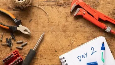 Screwdriver notebook screws and other tools on a wooden surface